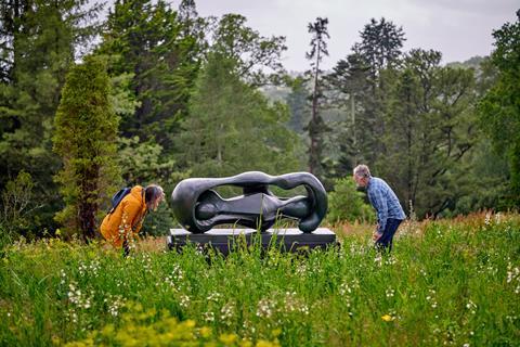 Two people stooping to look through Henry Moore scultpure